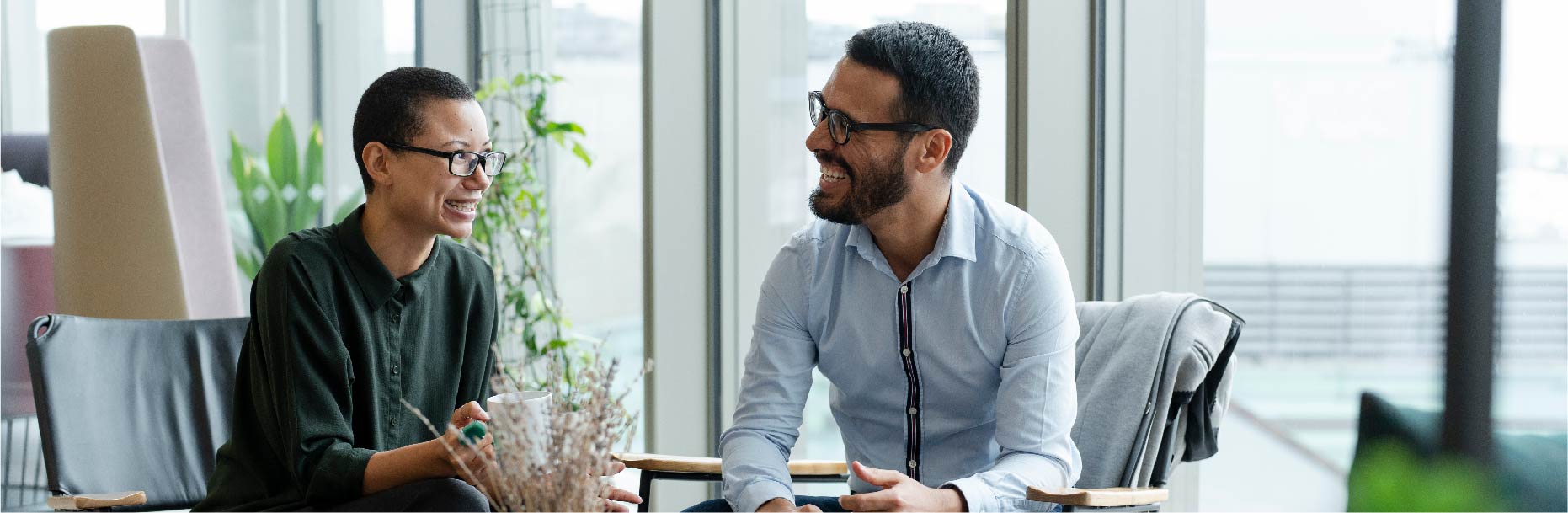 a man and women laughing together over a cup of coffee in an office